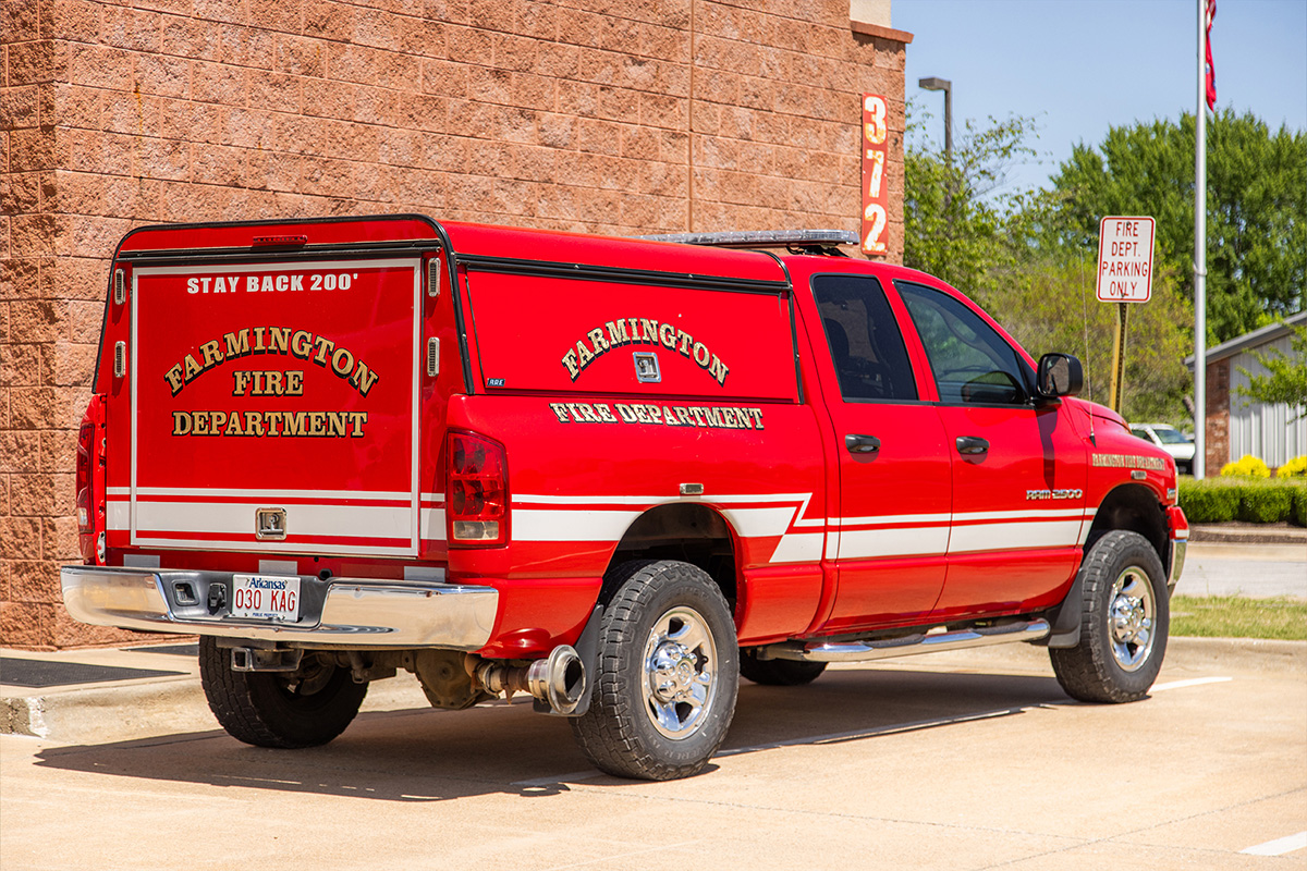 A bright red Farmington Fire Department pickup truck parked outside, with department's logo on the back window