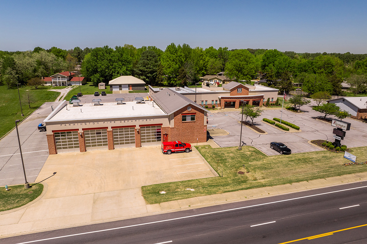 Aerial view of Farmington Fire Department with a red fire engine parked outside, adjacent to a street with passing cars and surrounded by residential buildings