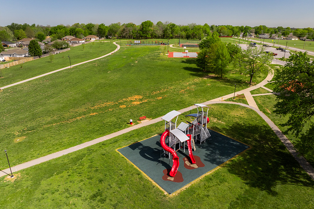 Aerial view of Farmington park featuring a large modern playground featuring a large red spiral slide